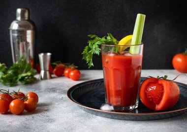 Klasik alkollü Bloody Mary kokteyli. Buzlu, limonlu ve kerevizli. Gri masa ve siyah arkaplan üzerinde kokteyl malzemeleri ve bar araçları