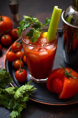 Klasik alkollü Bloody Mary kokteyli. Buzlu, limonlu ve kerevizli. Koyu renkli bir masada kokteyl malzemeleri ve bar araçları.