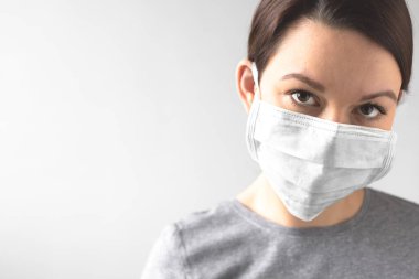 Coronavirus konsepti. Koruyucu tıbbi maske takan bir kız. Sağlığınızı koruyun. Virüsü ve salgın Covid-19 'u durdurun. Açık gri arkaplan