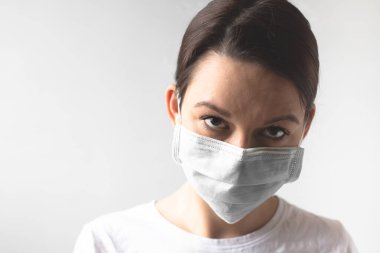 Coronavirus konsepti. Koruyucu tıbbi maske takan bir kız. Sağlığınızı koruyun. Virüsü ve salgın Covid-19 'u durdurun. Açık gri arkaplan