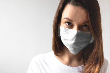 Coronavirus konsepti. Koruyucu tıbbi maske takan bir kız. Sağlığınızı koruyun. Virüsü ve salgın Covid-19 'u durdurun. Açık gri arkaplan