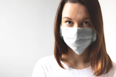 Coronavirus konsepti. Koruyucu tıbbi maske takan bir kız. Sağlığınızı koruyun. Virüsü ve salgın Covid-19 'u durdurun. Açık gri arkaplan