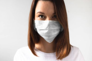 Coronavirus konsepti. Koruyucu tıbbi maske takan bir kız. Sağlığınızı koruyun. Virüsü ve salgın Covid-19 'u durdurun. Açık gri arkaplan