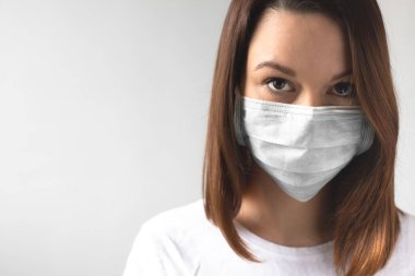 Coronavirus konsepti. Koruyucu tıbbi maske takan bir kız. Sağlığınızı koruyun. Virüsü ve salgın Covid-19 'u durdurun. Açık gri arkaplan