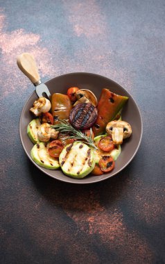 Izgara sebzeler (kabak, kiraz domatesleri, soğanlar, şampiyonlar, dolmalık biberiye ve deniz tuzu ile birlikte koyu renkli bir arka planda servis edilir). Üst Manzara. Boşluğu kopyala