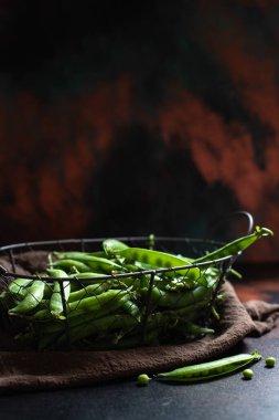 Siyah bir arka planda metal sepette taze organik yeşil bezelyeler. Yakın plan, kopyalama alanı