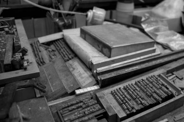 Eski bir tipografinin nesnelerin, harflerin ve metal tipi baskı bloklarının yakın çekimleri, siyah ve beyaz fotoğraf