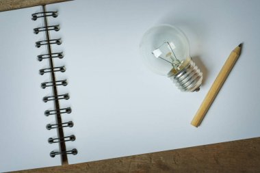 Bir ampul üzerinde açılan bir Sketchbook yerleştirilen küçük bir kalem ile