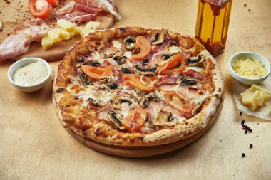 İtalyan parmalı jambonlu, mozzarellalı, mantarlı ve domatesli iştah açıcı pizzayı yakın plan bir restoranda. İtalyan mutfağı.