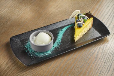 Yabanmersini ve çikolatalı iştah açıcı cheesecake, siyah tabakta vanilyalı dondurma. Ahşap arka. Kapatın. Boşluğu kopyala