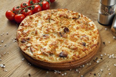 Eritilmiş peynirli pizza ve ahşap tepside domates. Bileşimli pizza, ahşap bir masada malzemelerle. Üst görünüm.