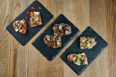 Çeşitli bruschettalar hazırladık. Ana yemeğin önünde İtalyan aperatifi. Biftek, domates sosu ve ahşap bir arka planda somon..