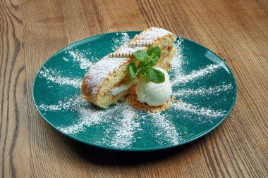 Sadece ahşap arka planda mavi tabakta bir porsiyon vanilyalı dondurmayla pişmiş sıcak kek. Lezzetli tatlı. Elma soslu Strudel 'i kapat.