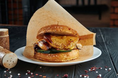 İştah açıcı ve sulu burger ızgara ananas, kabak, soğan ve tavuklu pirzola yanında patates kızartması. Kapat.