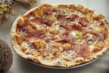 Erimiş peynir, prosciutto ve salamlı bir restorandaki keten gri masa örtüsüyle iştah açıcı bir manzara. Pizza kompozisyonu. İtalyan mutfağı. Yemek düzdü.