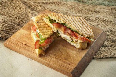 Sandviçi tavuklu, domatesli, marullu, ahşap bir tahtada, kırsal arka planda yakından izle.