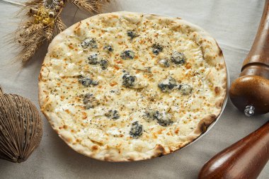 İştah açıcı 4 peynirli pizzaya yakından bakın. Bir restorandaki keten gri masa örtüsünün üzerinde armut olsun. Pizza kompozisyonu. İtalyan mutfağı. Yemek düzdü.