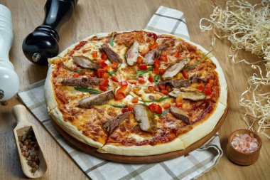 Eritilmiş peynirli, domuzlu, ahşap tepside domatesli ve malzemeli iştah açıcı pizza. Üst Manzara. Yemek düzdü.