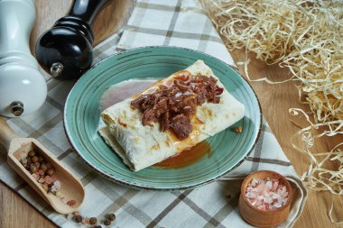Baharatlı burrito ya da baharatlı kompozisyonda geleneksel haşlanmış yumuşak sığır eti ile mavi tabakta shawarma. Manzarayı kapat. Yemek fotoğrafı. Düz yatıyordu