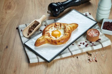 Lezzetli geleneksel Adjarian Khachapuri 'ye yakından bakın - eritilmiş tuzlu peynirli açık turta (suluguni) ve ahşap tahtada yumurta sarısı. Geleneksel Gürcü yemekleri