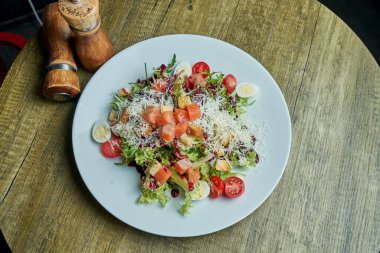 Biraz tuzlanmış somon, marul, parmesan, kiraz ve bıldırcın yumurtalı sağlıklı ve besleyici salata. Lezzetli deniz ürünleri salatası. Üst Manzara. Ahşap arkaplan