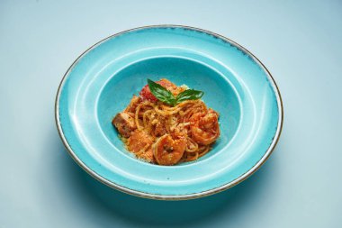 Domatesli ve karidesli iştah açıcı makarna, gri arka planda mavi kasede parmesan peyniri. İtalyan mutfağı