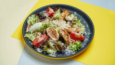Ceasar salatası, kızarmış ekmek, parmesan, tavuk, siyah tabakta siyah arka planda yumurta. Restoran servisi. Kapat.