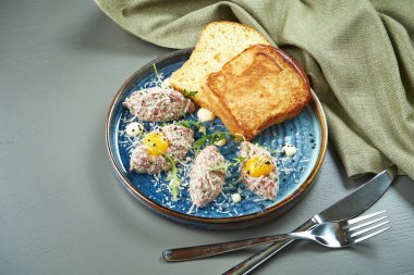 Ekmek, yumurta ve tabakla taze sığır etli tartar yakından bakın. Ahşap arka planda ev yapımı tartar eti.