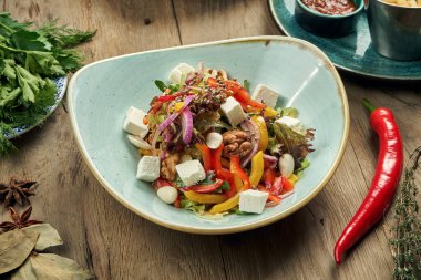 Klasik Yunan salatası, domates, soğan, salatalık, beyaz tabakta beyaz zeytin ve ahşap zemin. Manzarayı kapat. Yemek düzdü.