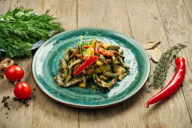 Sağlıklı sıcak salata, ızgara sığır eti ve mavi tabakta sebze. Ahşap bir arka planda salata ve baharatlı kompozisyon.