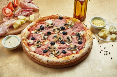 İştah açıcı pizzayı İtalyan parma jambonu, zeytin, mantar ve domatesle yakın plan bir restoranda. İtalyan mutfağı.