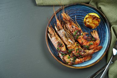 Ahşap arka planda mavi tabakta limonlu ızgara kaplan karidesi. Fotokopi alanı olan lüks deniz ürünleri manzarası. Düz yatıyordu