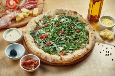 Geleneksel İtalyan pizzası roka, mozzarella, trüf ve ahşap zemin üzerinde güneşte kurutulmuş domates. Yüksek pas atıldı.