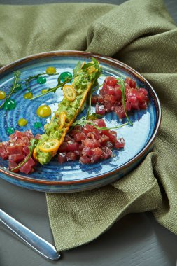 Taze ton balıklı ekmek, ahşap zemin üzerinde mavi tabakta soğan. Restoran yemeği. Yaklaş, seçici odaklanma. Dikey