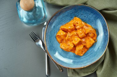 Ahşap bir arka planda mavi bir kasede farklı dolgularla (et, balık) soslu portakallı ravioli. İtalyan mutfağı. Üst görünüm, düz görünüm, boşluğu kopyala