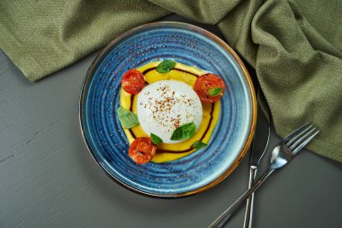 Ahşap arka planda mavi tabakta şeftali kremalı mozzarella ile İtalyan burrata peyniri. Lüks Restoran Yemekleri. Üst manzara, düz yatış. Boşluğu kopyala