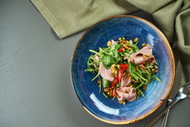 İştah açıcı salata, dana ızgara ve sebze, ıspanak ve çam fıstığı ahşap arka planda mavi bir kasede. Sağlıklı beslenme. Üst görünüm, alanı kopyala