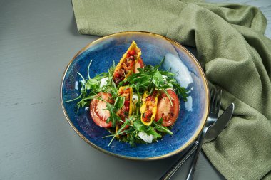 İştah açıcı İtalyan caprese salatasına yakından bakın. Taze domatesler, yumuşak mozzarella, roka ve mavi kâse rustik arka planda sos. Seçici odak, kapat