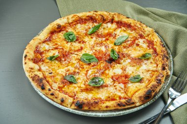 Restoranda domatesli pizza margherita ve ahşap arka planda fesleğen. İtalyan mutfağı.