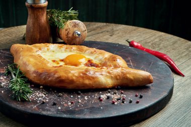 Geleneksel Adjarian Khachapuri 'ye yakın durun - eritilmiş tuzlu peynirli açık turta (suluguni) ve ahşap tepside yumurta sarısı. Geleneksel Gürcü yemekleri