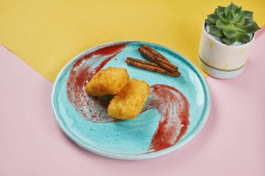 İştah açıcı Asya tatlısı- koyu yağda kızartılmış muhallebi sütlü ahududu soslu renkli arka planda mavi bir tabakta. Youtiao. Kızarmış Süt