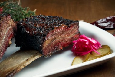 Lezzetli, iştah açıcı, füme ve ızgara sığır pirzolasına yakından bakın. Barbekü kaburgaları. Beyaz tabakta klasik bir Amerikan mutfağı. Seçici odak