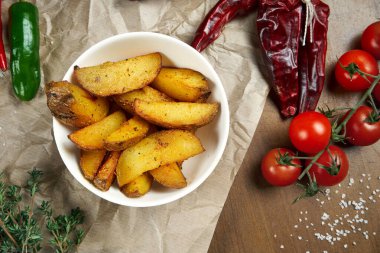 Baharatlı patatesler, sebze ve spesiyaliteyle kompozisyonda beyaz bir kasede. Tarif fotoğrafı