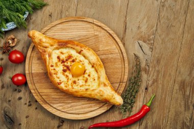 Lezzetli geleneksel Adjarian Khachapuri 'nin üst görüntüsü - eritilmiş tuzlu peynirli açık turta (suluguni) ve ahşap tepside yumurta sarısı. Geleneksel Gürcü yemekleri