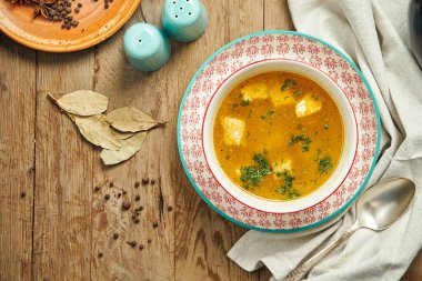 Ahşap arka planda kırmızı bir kasede balık çorbası. Sağlıklı deniz ürünleri çorbası, restoran servisi. Ukha