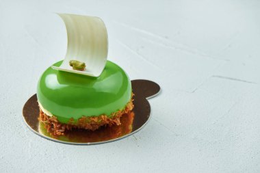 İştah açıcı yeşil pasta, parlak dokulu, beyaz çikolata ve beyaz desenli şam fıstığı aromalı. Nefis tatlı hamur işleri.