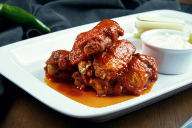 Harika bira atıştırmalığı. Baharatlı bufalo kanadı. Beyaz tabakta salata ile süslenmiş barbekü kanatları. Kapatın. Bar yemeği.