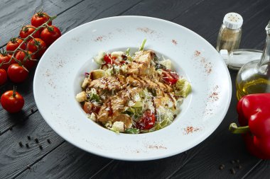 Mısır ekmekli Sezar salatası, parmesan peyniri, tavuk, yumurta hazmedici maddelerle bembeyaz bir kasede. Restoran servisi. Kapat, siyah arkaplan