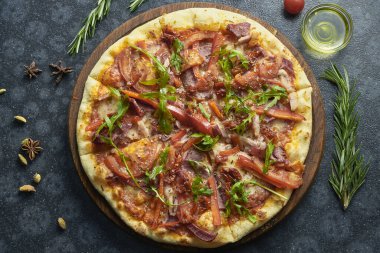 Dört çeşit etli ev yapımı pizza, erimiş peynir, kırmızı sos, domates ve roka karışımı içerikli siyah bir arka planda. Üst görünüm düzlüğü