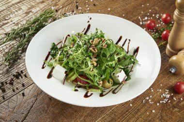 Marullu yeşil çiftlik salatası, taze sebze, tatlı soğan ve beyaz kasede beyaz bir peynir ahşap arka planda baharatlı kompozisyon